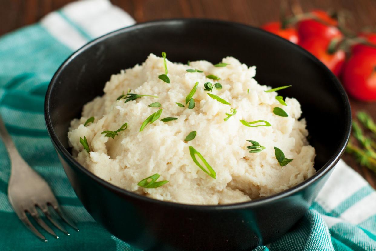 cauliflower mash with herbs in bowl on kitchen cloth, fork beside bowl