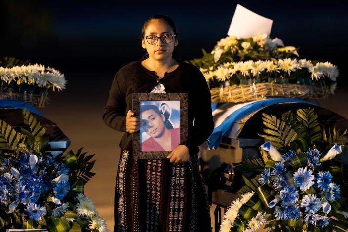 A Foreign Ministry officer holds a portrait beside the coffin of a Guatemalan migrant whose remains arrived at the La Aurora Air Force Base in Guatemala City on Tuesday. The Mexican air force transported the bodies of 17 migrants who died in a fire at an immigration detention center in Juárez.