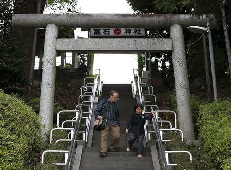 72-year-old Kanemasa Ito (L) and his 68-year-old wife Kimiko who was diagnosed with dementia 11 years ago, climb down the stairs under a Torii gate at a shrine as they go shopping near their home in Kawasaki, south of Tokyo, Japan, April 6, 2016. REUTERS/Issei Kato