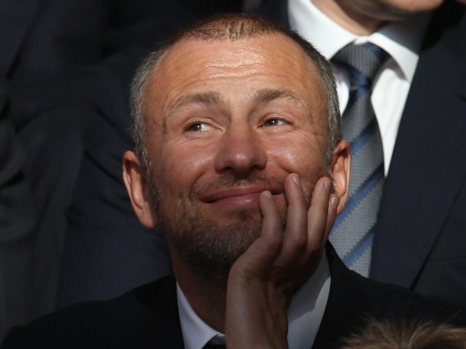 A picture of Andrey Melnichenko smiling with his hands on his chin.