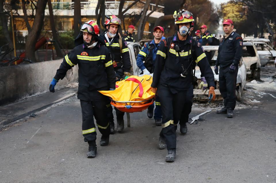 Firefighters carry a forest fire victim near Mati, Greece. (Photo: John Liakos/Intime/AthenaPictures/REX/Shutterstock )