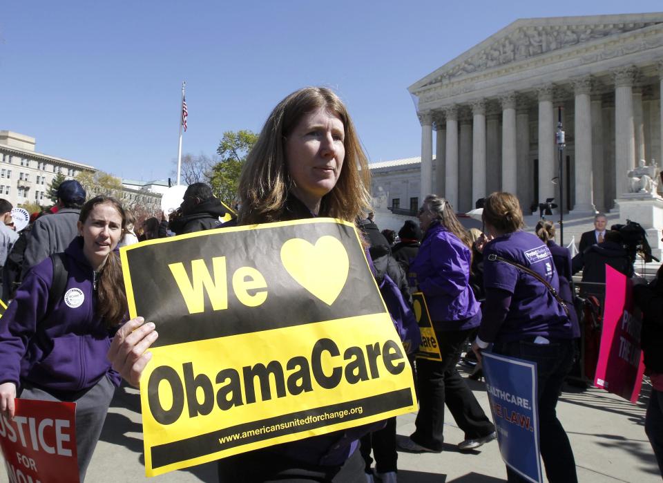 Holding a sign saying "We Love ObamaCare" supporters of health care reform rally in front of the Supreme Court in Washington, Tuesday, March 27, 2012, as the court continued hearing arguments on the health care law signed by President Barack Obama. Go ahead, call it Obamacare. Obama’s re-election campaign has lifted an unofficial ban on using the opposition’s derisive term for his health care law. Democratic activists have been chanting, "We love Obamacare," in front of the Supreme Court. And the campaign is selling T-shirts and bumper stickers that proclaim: "I like Obamacare." (AP Photo/Charles Dharapak)