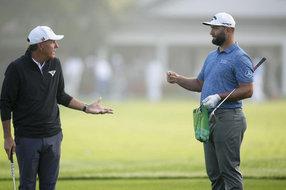 Phil Mickelson and Jon Rahm, of Spain, talk on the range before a practice round for the Masters golf tournament at Augusta National Golf Club on Wednesday, April 5, 2023, in Augusta, Ga. (AP Photo/Jae C. Hong)