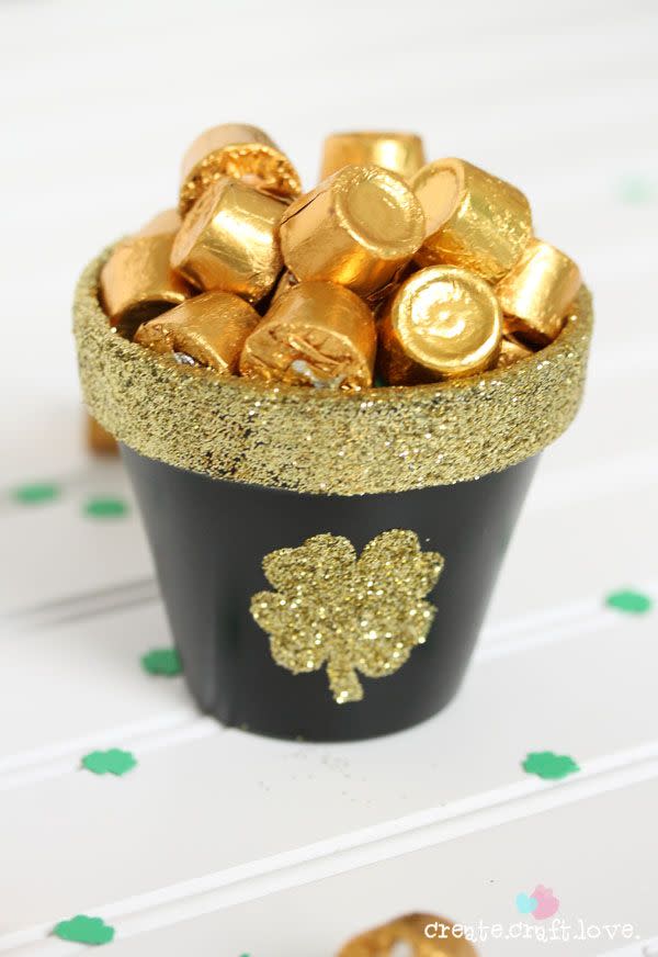 terra cotta pot painted black with glittery gold rim and shamrock decoration, filled with rolos candy for st patrick's day