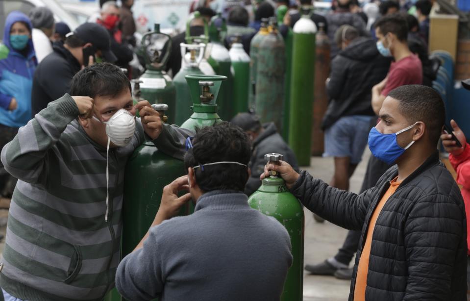 Personas haciendo cola para llenar tanques de oxígeno en el Callao, Perú, el 3 de junio del 2020. El oxígeno escasea en los hospitales de Perú en plena pandemia del coronavirus y la gente a menudo tiene que procurárselo por su cuenta. (AP Photo/Martín Mejía)