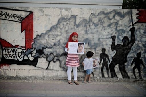 Bahraini children hold up pictures of tortured democracy activists as they pose in front of graffiti depicting a scene of anti-government demonstrations in the Shiite village of Barbar on the western outskirts of the Gulf kingdom Violence marred Bahrain's controversial Grand Prix race as a fire bomb exploded near Force India team members and protesters clashed with police