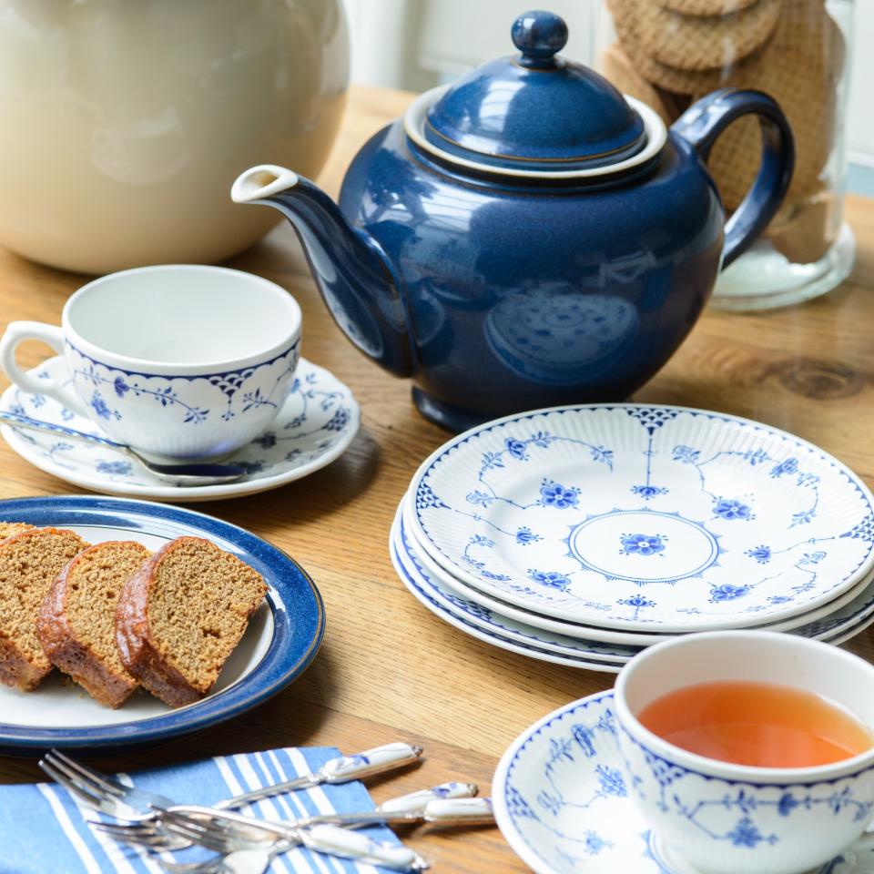 A teapot with teacups served with cake and biscuits