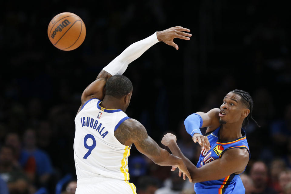 Oklahoma City Thunder guard Shai Gilgeous-Alexander, right, passes away from Golden State Warriors forward Andre Iguodala (9) in the first half of an NBA basketball game Tuesday, Oct. 26, 2021, in Oklahoma City. (AP Photo/Nate Billings)