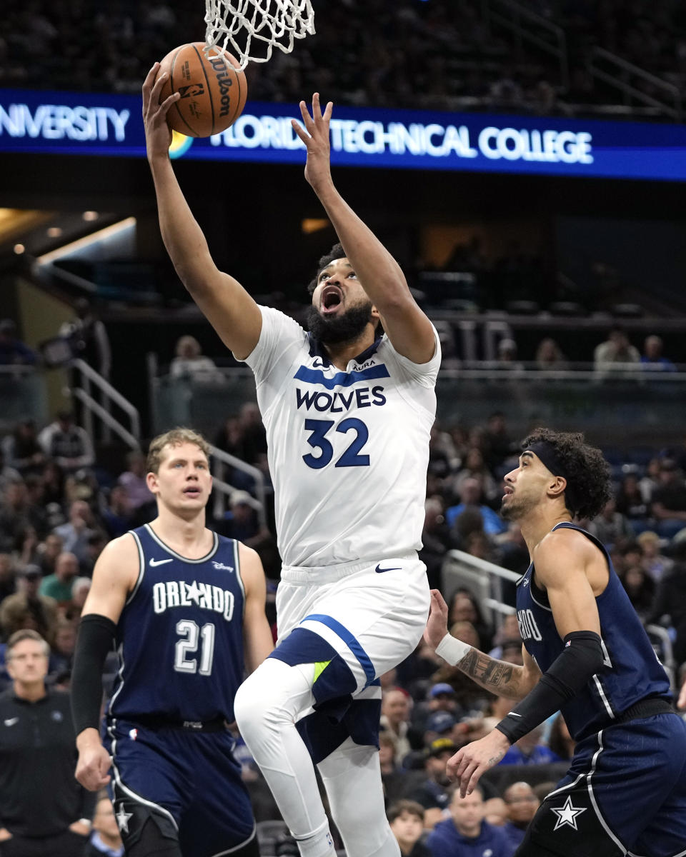 Minnesota Timberwolves' Karl-Anthony Towns (32) makes a shot as he gets between Orlando Magic center Moritz Wagner (21) and guard Trevelin Queen, right, during the first half of an NBA basketball game, Tuesday, Jan. 9, 2024, in Orlando, Fla. (AP Photo/John Raoux)