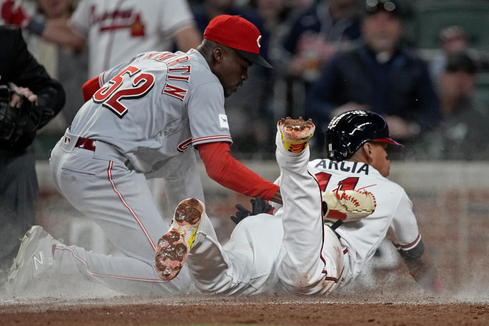 Atlanta Braves' Orlando Arcia, right, beats the tag from Cincinnati Reds relief pitcher Reiver Sanmartin (52) to score on a wide pitch in the seventh inning of a baseball game Monday, April 10, 2023, in Atlanta. (AP Photo/John Bazemore)