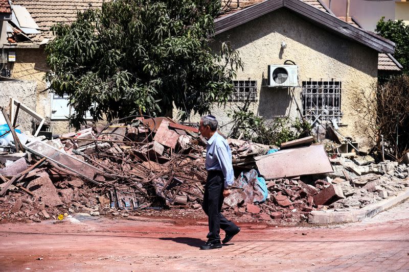 A man walks by a home that was damaged when a rocket, fired from Gaza, hit it in Ashkelon