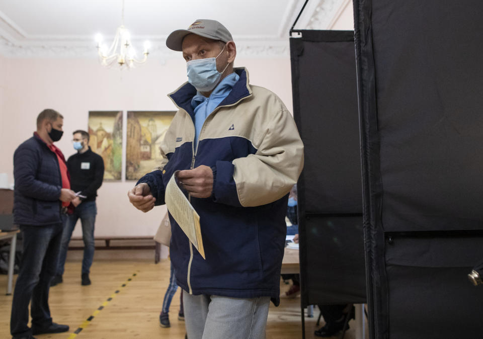 A man, wearing face masks to protect against coronavirus leaves the polling booth at a polling station during parliamentary elections in Vilnius, Lithuania, Sunday, Oct. 11, 2020. Polls opened Sunday for the first round of national election in Lithuania, where voters will renew the 141-seat parliament and the ruling four-party coalition is widely expected to face a stiff challenge from the opposition to remain in office. (AP Photo/Mindaugas Kulbis)