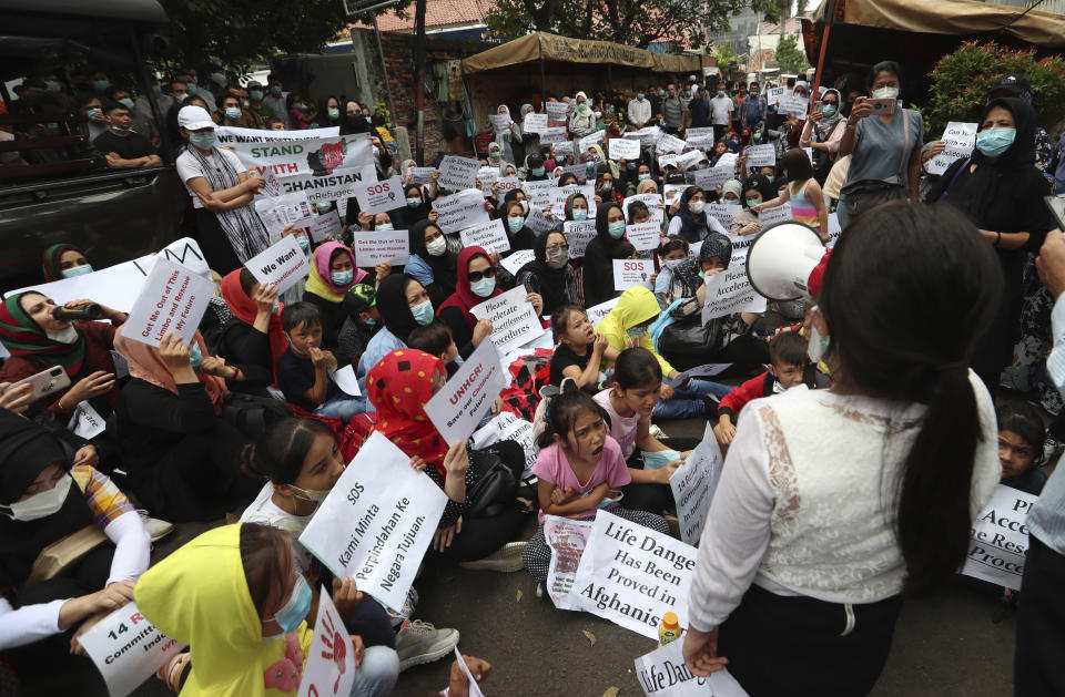 Afghan women and children refugees living in Indonesia hold posters during a rally outside a building that houses UNHCR representative office in Jakarta, Indonesia, Monday, Nov. 15, 2021. Hundreds of Afghan refugees and asylum seekers living in Indonesia rallied in front of the U.N. refugee agency office in Jakarta on Monday to urge it to speed up their resettlement.(AP Photo/Achmad Ibrahim)