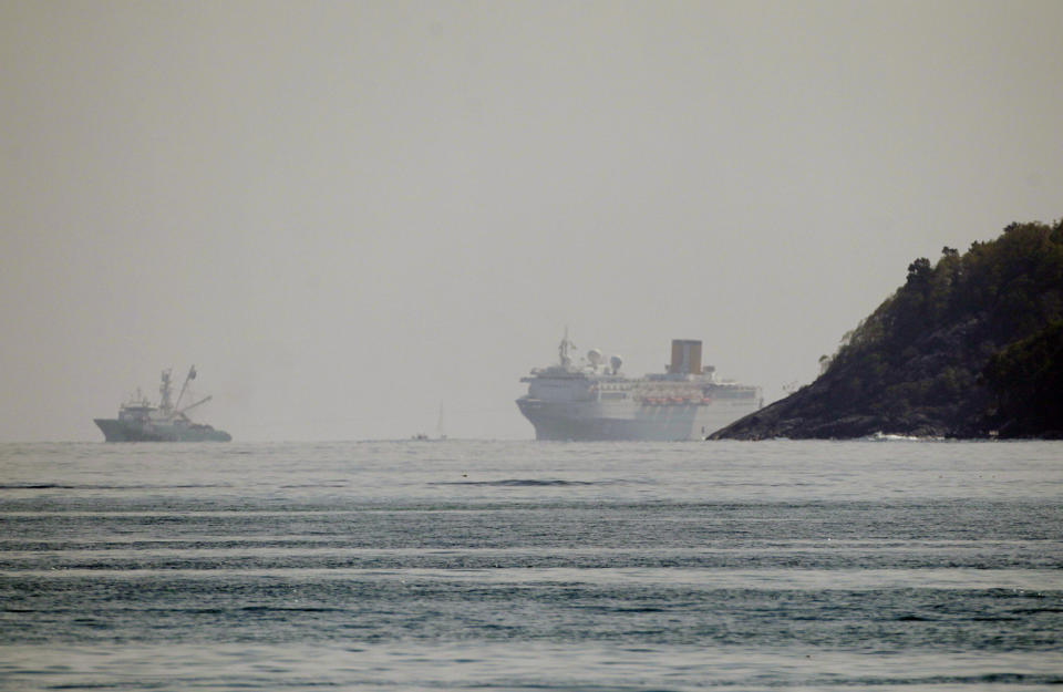 The Costa Allegra Cruise ship, right, is towed in the Victoria's harbor, Seychelles Island, Thursday, March 1, 2012. The disabled cruise ship is arriving in port in the island nation of the Seychelles after three days at sea without power. The Costa Allegra has been at sea with more than 1,000 people onboard and without electricity since a fire in the generator room on Monday. (AP Photo/Gregorio Borgia)