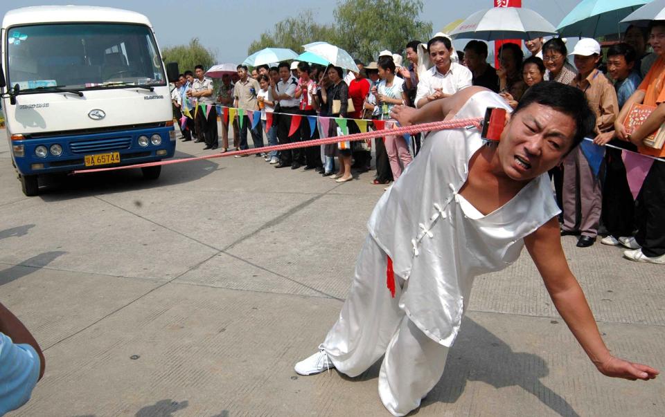 Guinness world record keeper Li Jianhua pulls a bus with his right ear at the Moshan Park in Wuhan, central China's Hubei province on September 30, 2005.