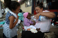 <p>A Central American migrant woman gives water to a baby as the annual Migrant Stations of the Cross caravan sets up camp for a few days at a sports center in Matias Romero, Oaxaca state, Mexico, late Monday, April 2, 2018. (Photo: Felix Marquez/AP) </p>