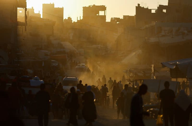 People walk at the remains of a market after an Israeli strike, in Khan Younis