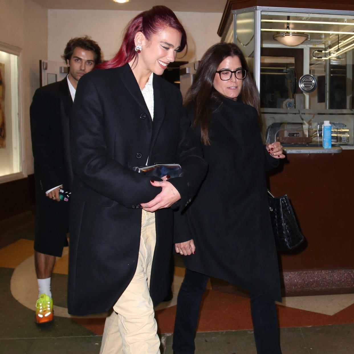  Dua Lipa wearing an oversized black blazer with a silver clutch. 