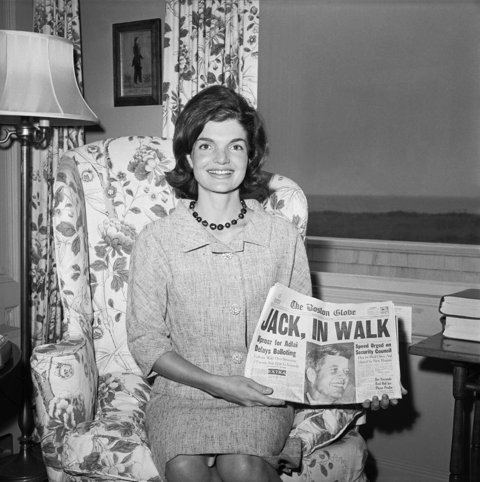 Kennedy holds up a newspaper with a picture of her husband during the presidential campaign.