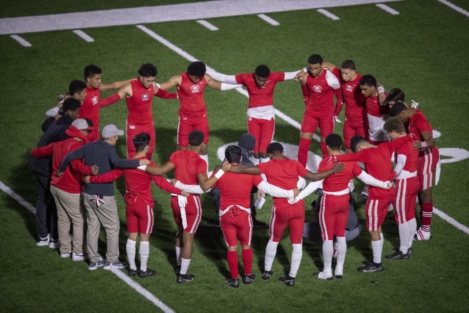 Mater Dei football players huddle during warmup exercises.