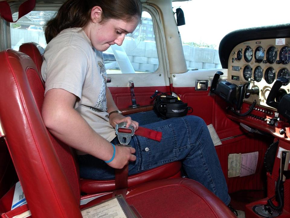 Emily Maguire straps on her seatbelts in the cockpit of a Cessna 172 before taking off with her flight instructor in the Aviation Career Education Camp at Maine Aviation.