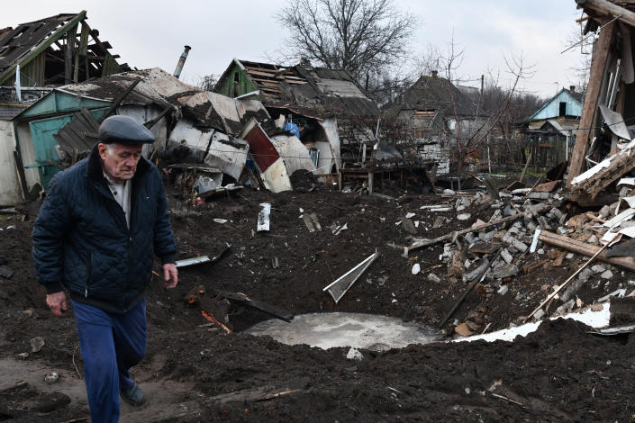 A man walks near a crater and his house that was damaged after Russian shelling in Kramatorsk, Ukraine, Saturday, Nov. 19, 2022. (AP Photo/Andriy Andriyenko)