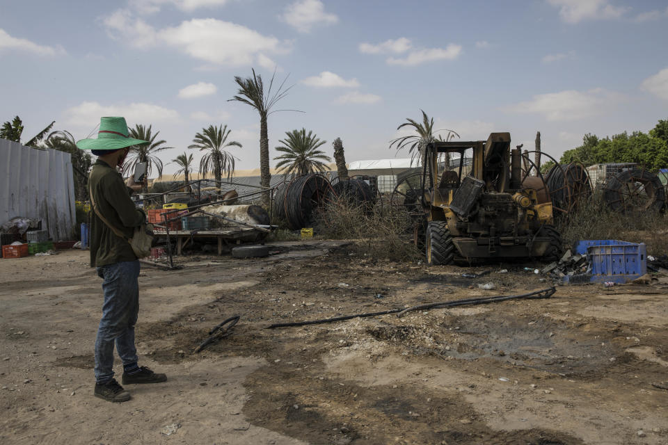 Thai worker looks at the damage caused by a missile fired from gaza Strip at a farm near the Israel and Gaza border, Thursday, Aug. 9, 2018. Israeli warplanes struck dozens of targets in the Gaza Strip and three people were reported killed there, while Palestinian militants from the territory fired scores of rockets into Israel in a fierce burst of violence overnight and into Thursday morning. (AP Photo/Tsafrir Abayov)