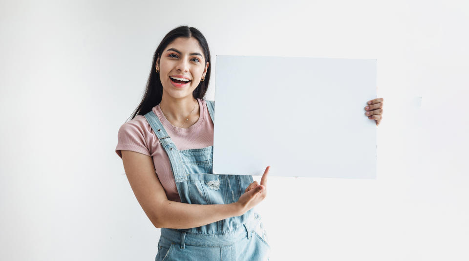 Young latin woman holding a blank empty card isolated on white background in Latin America