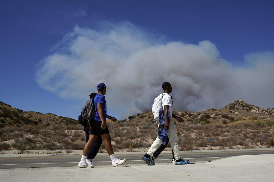 Students from Castaic High School walks past a plume caused by the Route Fire Wednesday, Aug. 31, 2022, in Castaic, Calif. (AP Photo/Marcio Jose Sanchez)