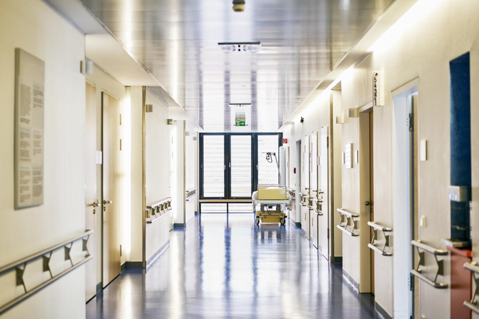 The hallway of a hospital with a gurney near the wall