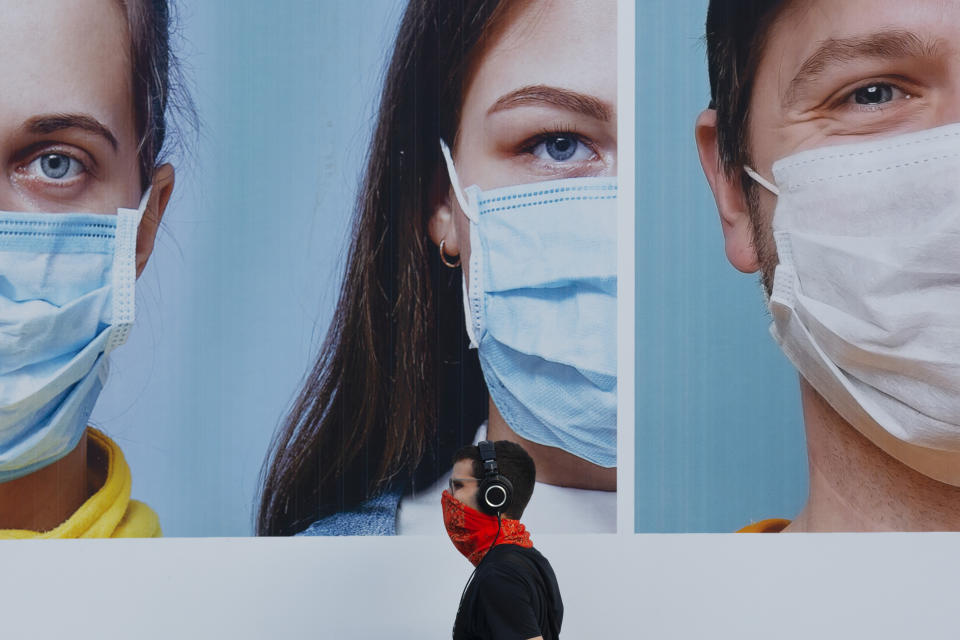 A man wearing an improvised face mask walks by a billboard raising the awareness of wearing face masks and washing hands following government measures to help stop the spread of the coronavirus, in Ramat Gan, near Tel Aviv, Israel, Thursday, July 16, 2020. Israel reached a new daily record of confirmed coronavirus cases on Thursday as the government discussed renewed lockdown measures to contain the growing outbreak. (AP Photo/Oded Balilty)