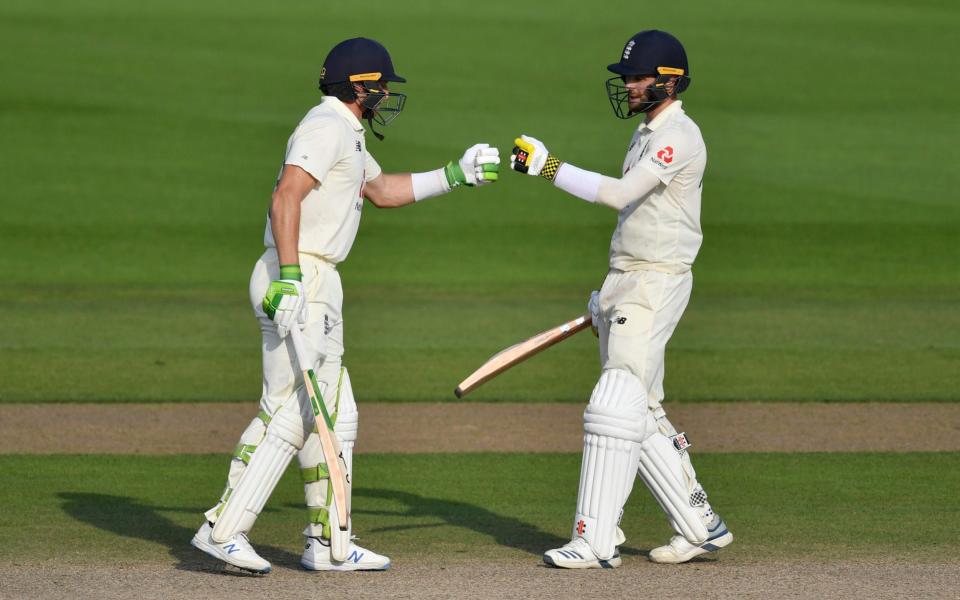 England's Jos Buttler, left, and Chris Woakes fist bump during the fourth day of the first cricket Test match between England and Pakistan  - Getty Pool 