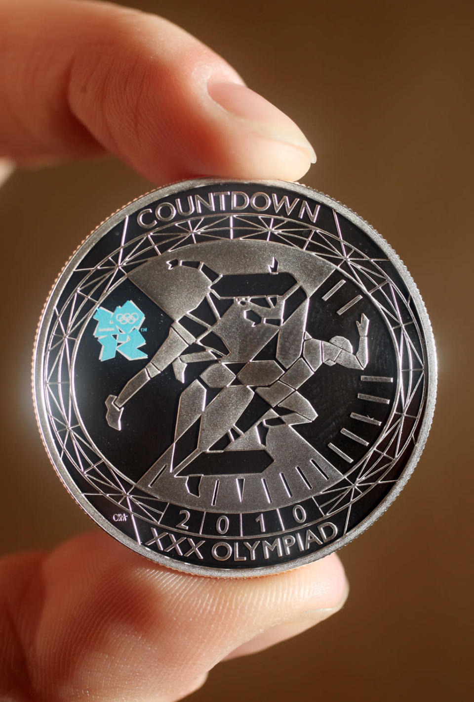 A woman holds a London 2012 countdown commemorative coin at the launch of the London Olympic Games official merchandise on July 30, 2010 in London, England. (Photo by Oli Scarff/Getty Images)