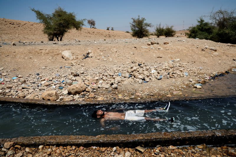 FILE PHOTO: A Palestinian man cools off during a heat wave, in al-Oja springs near Jericho in the Israeli-occupied West Bank