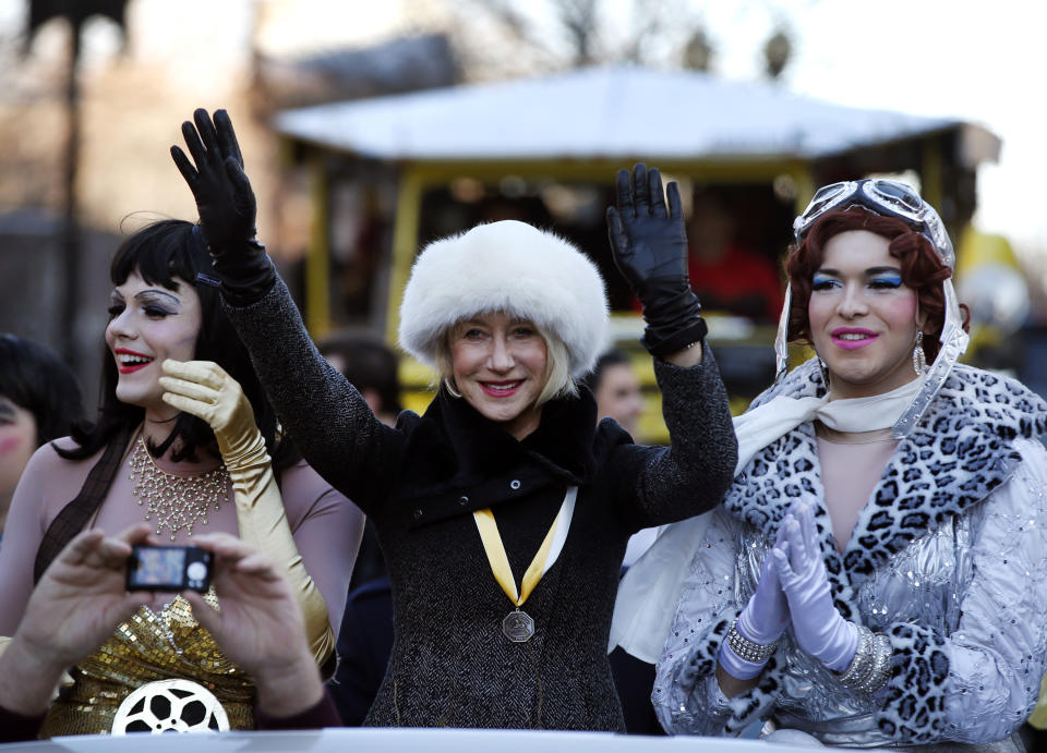 Actress Helen Mirren waves as she is accompanied by drag actors Tony Oblen, left, and Ethan Hardy, right, as she is paraded through Harvard Square as woman of the year by Harvard University's Hasty Pudding Theatricals in Cambridge, Mass., Thursday, Jan. 30, 2014. (AP Photo)