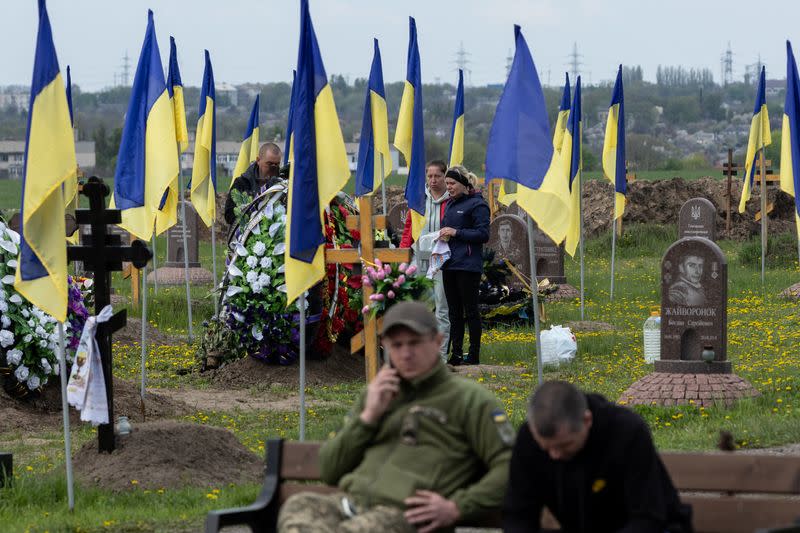 Darina visita la tumba de su esposo, un oficial de policía ucraniano que murió recientemente en una misión para rescatar a evacuados, mientras los ucranianos visitan el cementerio para honrar a sus familiares muertos el primer domingo después de Pascua, en medio de la invasión rusa de Ucrania, en Dnipro, Ucrania