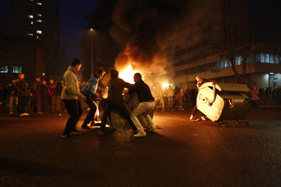 In this photo taken on Thursday, Feb. 6. 2014, Bosnian protesters build a burning road blockade during a protest in Bosnian town of Tuzla, 140 kms north of Sarajevo. Violent protests by some thousands of unpaid workers in a northern Bosnian city spread to other parts of the country Thursday and have morphed into widespread discontent about unemployment and alleged rampant corruption, in an election year. Police used tear gas to temporarily disperse the protesters in Tuzla who threw stones at a local government building, then the protesters returned after the tear gas volley, surrounded the empty government building and set tyres and trash on fire.(AP Photo/Amel Emric)