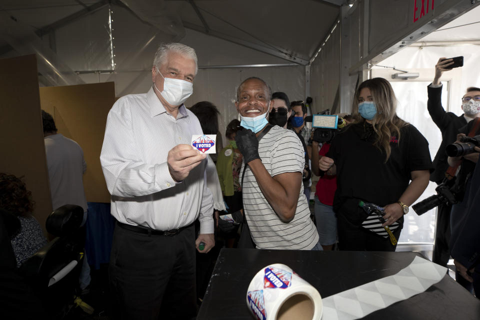 Nevada Governor Steve Sisolak, left, poses with poll worker Toni James after dropping off his ballot at an early voting site in Las Vegas Saturday, Oct. 17, 2020. (Steve Marcus/Las Vegas Sun via AP)