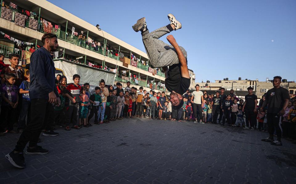 A group of young men performs a show to entertain children who fled their home with families in Gaza City