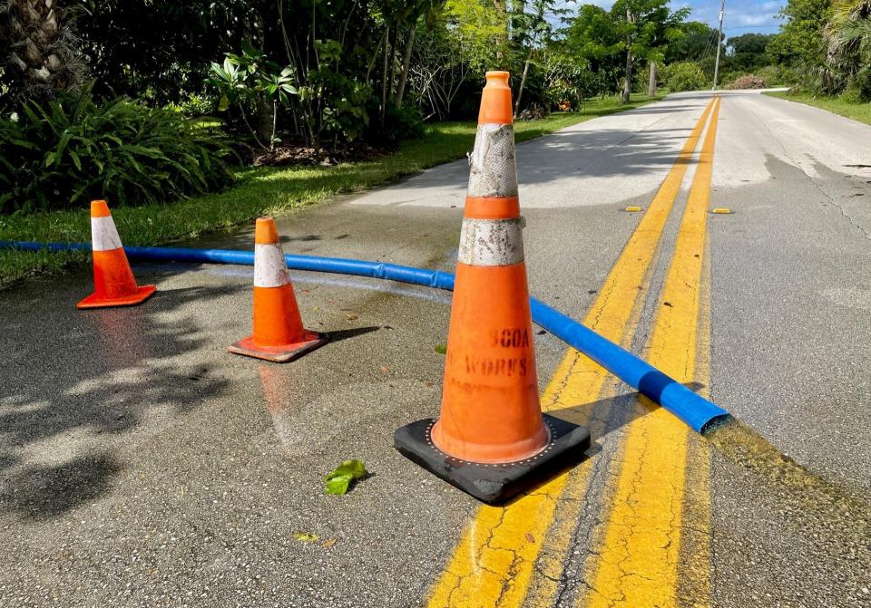 Orange cones on West Crisafulli Road mark where a blue drainage pipe pumped excess rainwater onto the asphalt Saturday from a private property.
