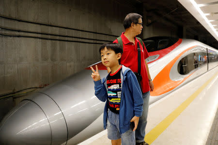 A boy poses beside a Guangzhou-Shenzhen-Hong Kong Express Rail train at West Kowloon Terminus on the first day of service of the Hong Kong Section of the Guangzhou-Shenzhen-Hong Kong Express Rail Link, in Hong Kong, China September 23, 2018. REUTERS/Tyrone Siu