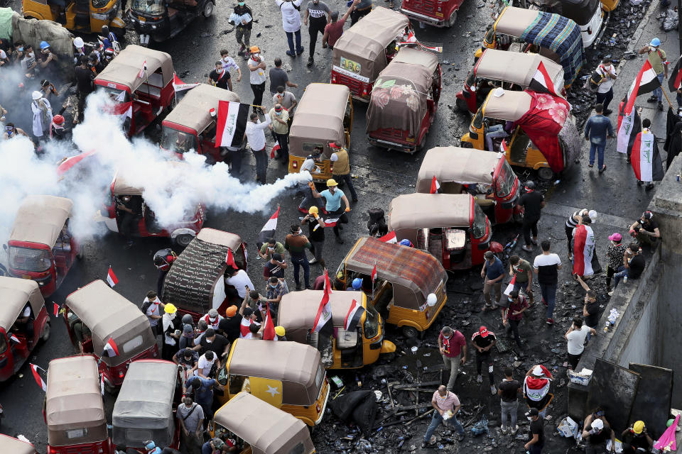 An anti-government protester prepares to throw back a tear gas canister fired by Iraq security forces to disperse a during a demonstration, in Baghdad, Iraq, Wednesday, Oct. 30, 2019. (AP Photo/Hadi Mizban)