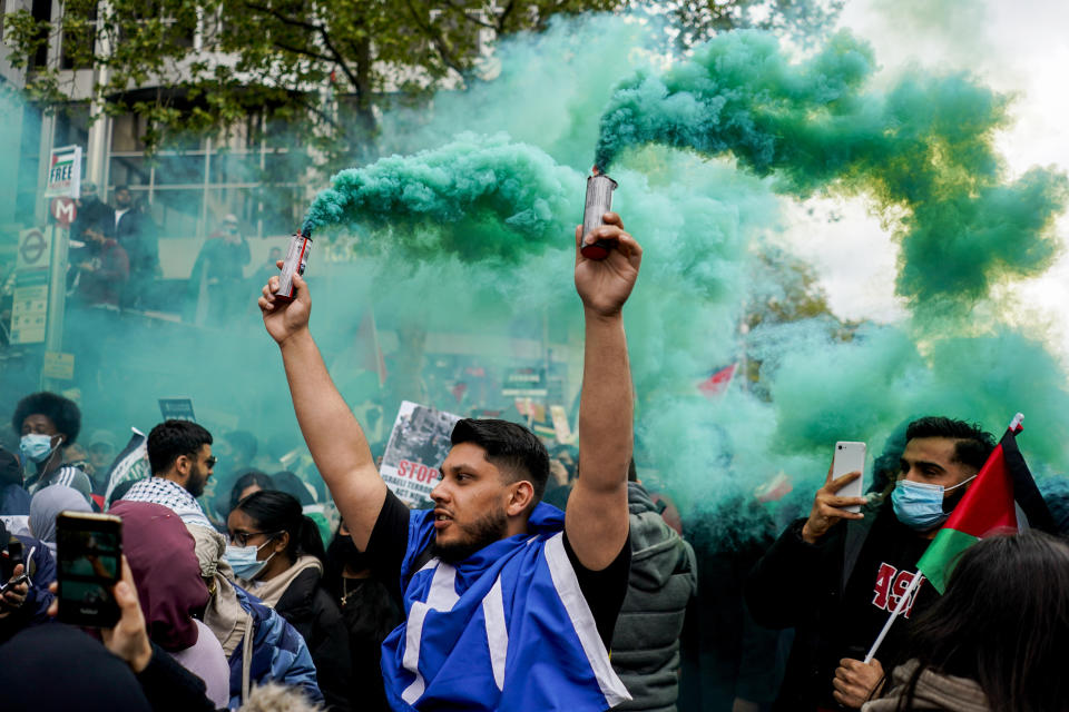 A demonstrator holds two flares during a march in solidarity with the Palestinian people amid the ongoing conflict with Israel, during a demonstration in London, Saturday, May 15, 2021. (AP Photo/Alberto Pezzali)