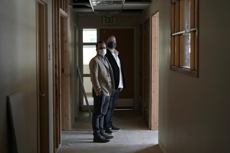 Scott Canfield, left, and Garth Reeves, co-founders of the Why Not You Academy charter school, pose for a photo, Tuesday, Oct. 27, 2020, inside the building being renovated to house the school in Des Moines, Wash., south of Seattle. Seattle Seahawks NFL football quarterback Russell Wilson and his Grammy-winning wife, pop singer Ciara, are putting their money and celebrity behind rebranding the charter school, which advocates hope will boost the troubled Washington state charter school sector that has suffered from enrollment problems after years of legal challenges. (AP Photo/Ted S. Warren)