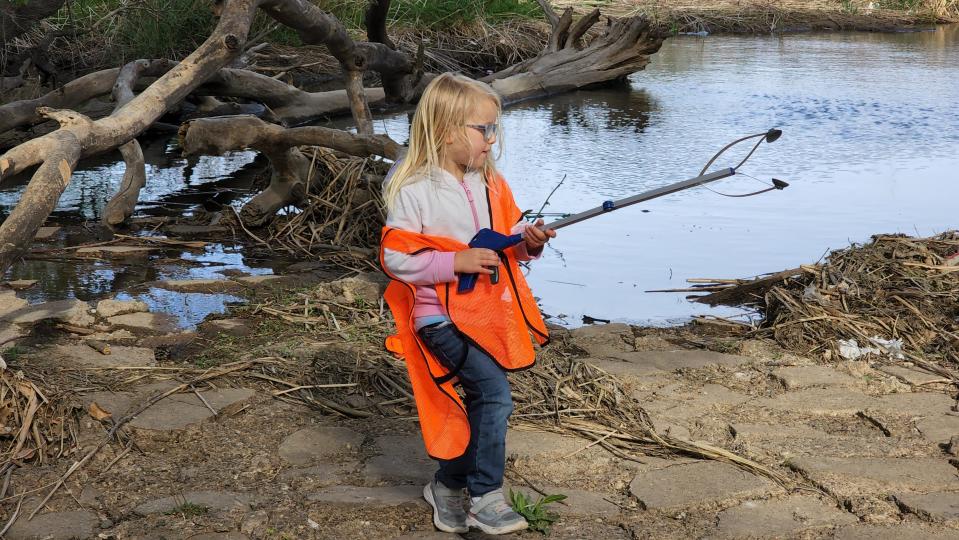 A young girl chips in Saturday to clean up Thompson Park in honor of Earth Day.