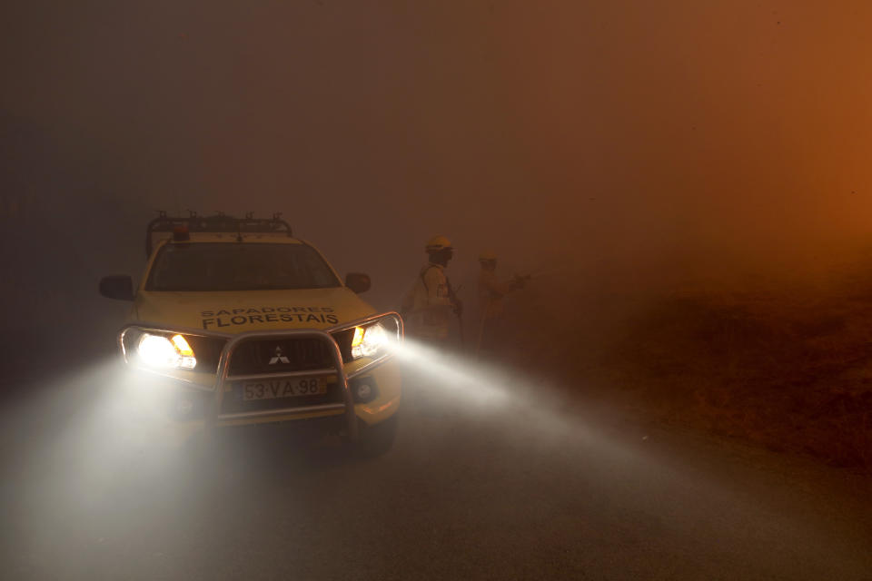 Firefighters battling a wildfire are engulfed in smoke, in Gouveia, in the Serra da Estrela mountain range, in Portugal on Thursday, Aug. 18, 2022. Authorities in Portugal said Thursday they had brought under control a wildfire that for almost two weeks raced through pine forests in the Serra da Estrela national park, but later in the day a new fire started and threatened Gouveia. (AP Photo/Joao Henriques)