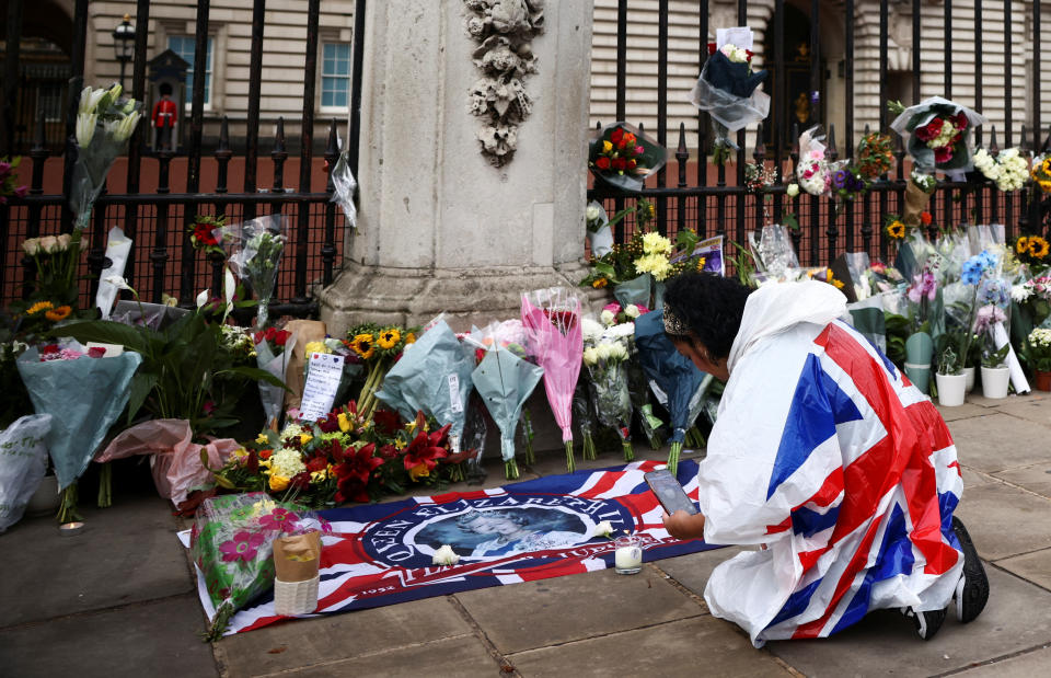 <p>A person wearing the Union Jack flag sits near the tributes in front of Buckingham Palace, following the passing of Queen Elizabeth, in London, Britain, September 9, 2022. REUTERS/Henry Nicholls - RC2JDW90KE9S</p> 