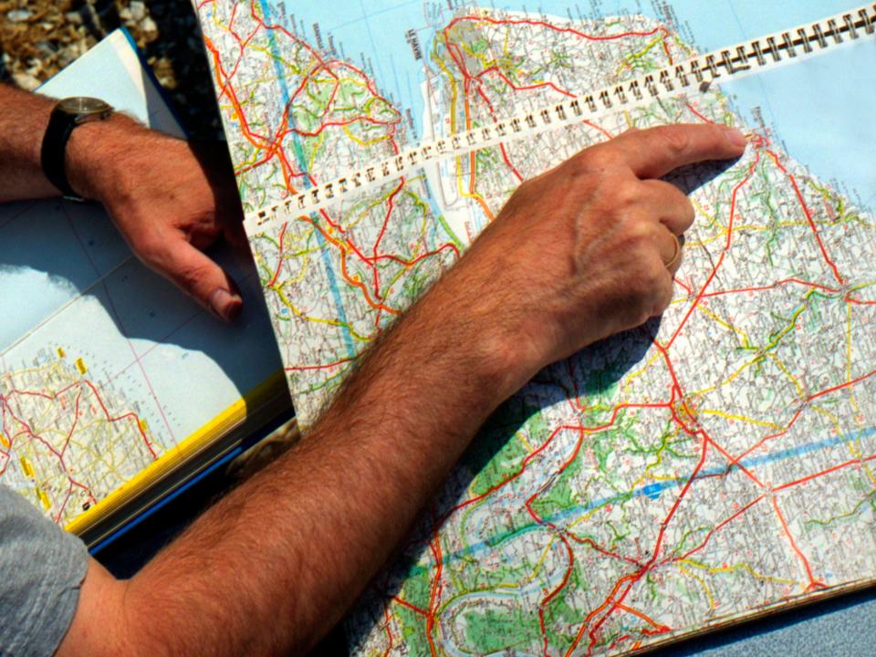 A hand points to a location on a road atlas