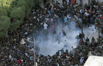 FILE - In this file photo dated Friday, Jan. 14, 2011, demonstrators scatter after police officers use teargas during a protest in Tunis. Tunisia's official news agency says President Zine El Abidine Ben Ali has declared a state of emergency as riots escalated in his North African nation. On Thursday Jan. 14, 2021, Tunisia commemorates 10 years since the flight into exile of its iron-fisted leader, Zine El Abidine Ben Ali, pushed from power in a popular revolt that foreshadowed the so-called Arab Spring. (AP Photo/Christophe Ena, FILE)