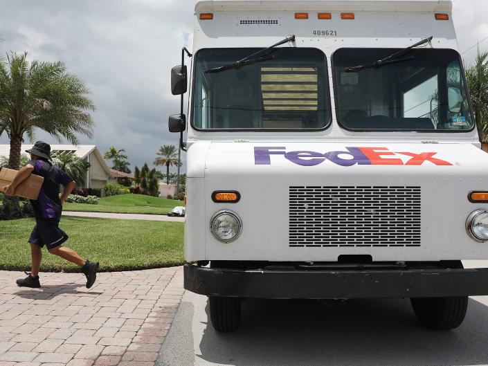 A FedEx worker delivers a box from a FedEx Ground truck.